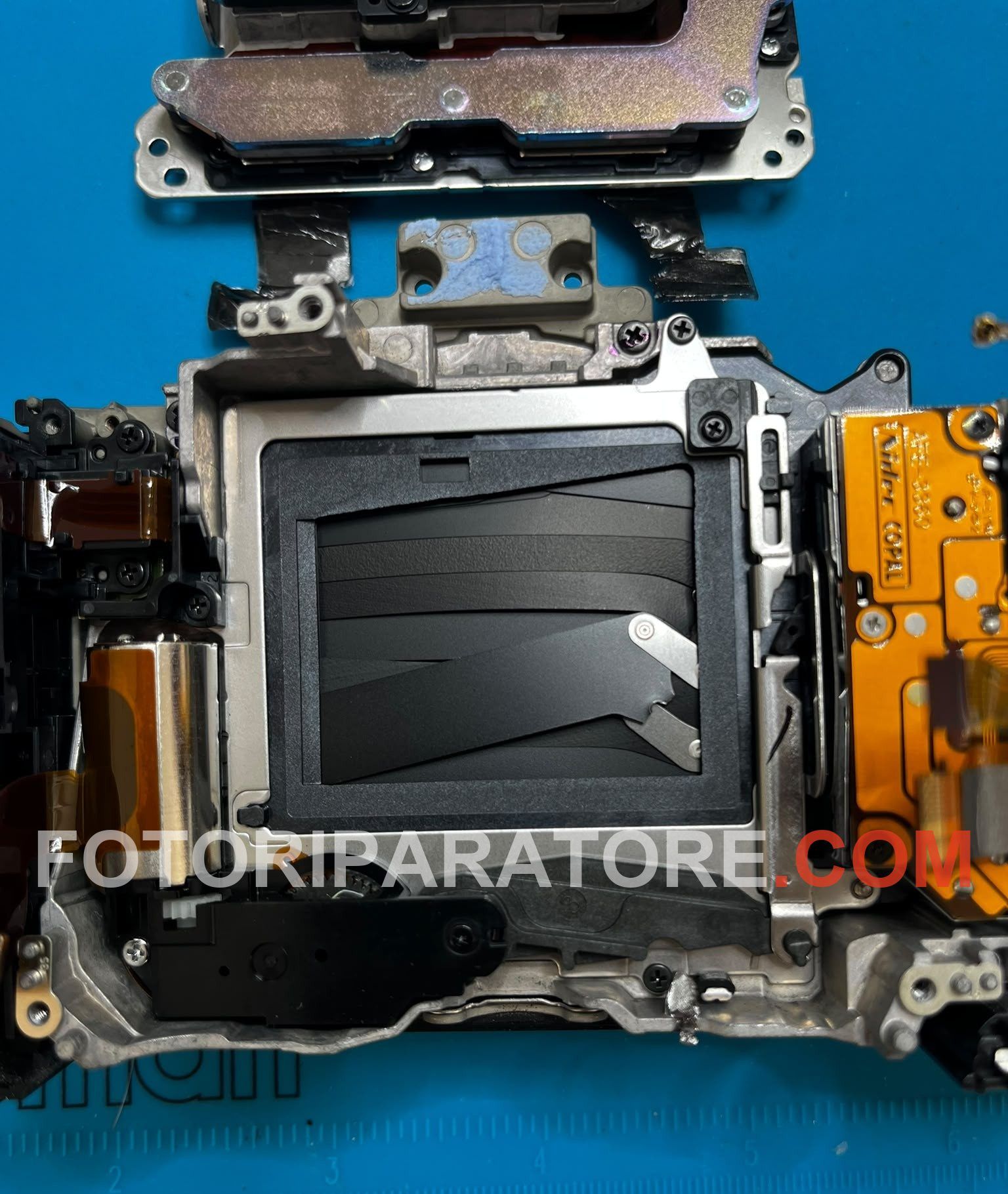 Otturatore rotto della Sony A7 III visto da vicino: lamelle accartocciate e leva di comando deformata